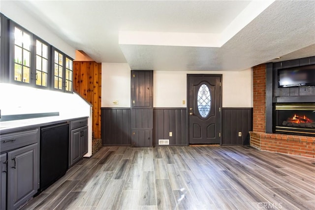 222 Holiday Dr, Lake Arrowhead, CA 92352 - foyer featuring a wainscoted wall, a fireplace, wood finished floors, and a textured ceiling