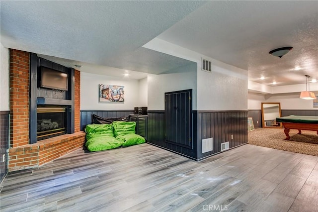 222 Holiday Dr, Lake Arrowhead, CA 92352 - living room featuring a textured ceiling, a fireplace, wood finished floors, billiards, and wainscoting