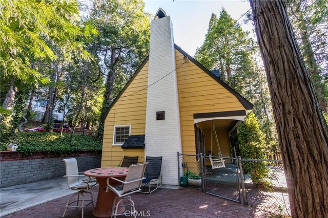 222 Holiday Dr, Lake Arrowhead, CA 92352 - back of house with a chimney, a patio area, a gate, and fence