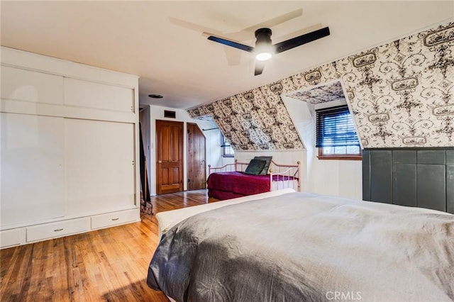 222 Holiday Dr, Lake Arrowhead, CA 92352 - bedroom featuring wallpapered walls, wainscoting, wood finished floors, and ceiling fan