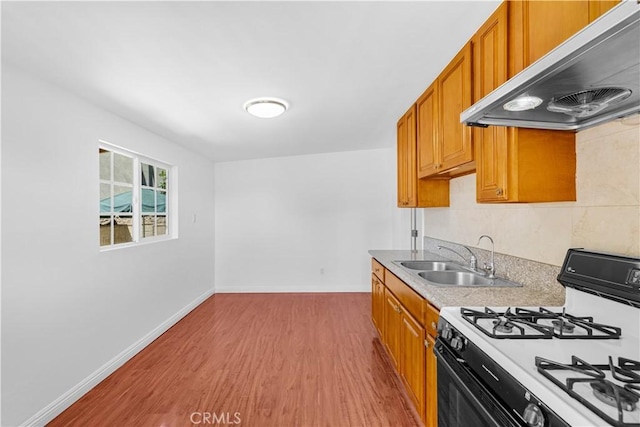 507 S Gaybar Ave, West Covina, CA 91790 - kitchen with gas stove, under cabinet range hood, a sink, light wood finished floors, and brown cabinetry