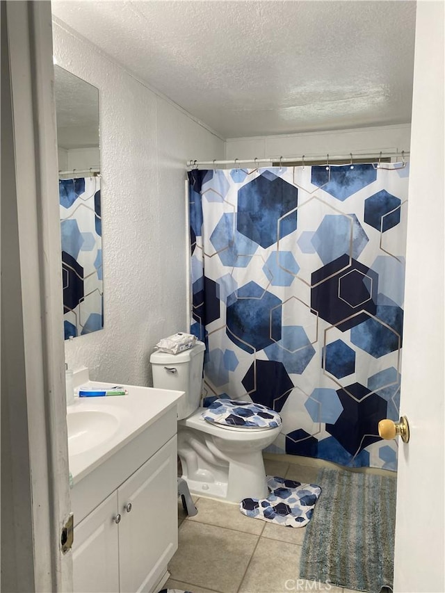 bathroom with a textured wall, a textured ceiling, vanity, toilet, and tile patterned floors