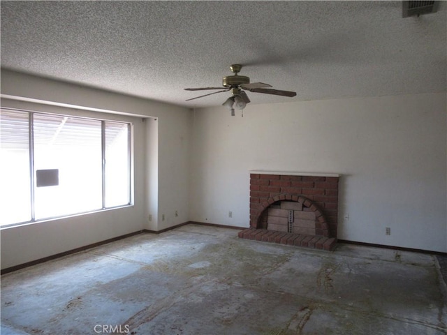 unfurnished living room featuring a ceiling fan, concrete floors, a textured ceiling, a fireplace, and baseboards
