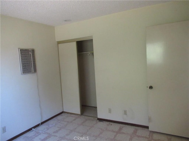 unfurnished bedroom with a textured ceiling, a closet, and baseboards