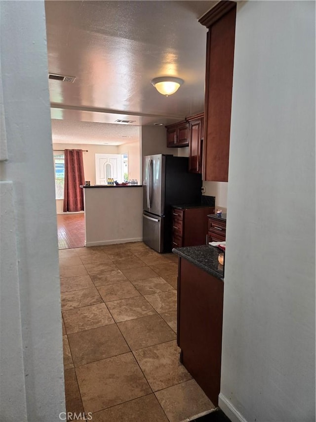 9715 La Docena Ln, Pico Rivera, CA 90660 - kitchen with dark countertops, light tile patterned floors, freestanding refrigerator, and a peninsula