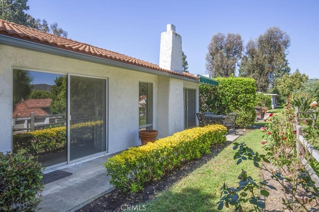 3424 Calle Azul Unit A, Laguna Woods, CA 92637 - view of side of home with stucco siding, a chimney, a tile roof, and a lawn