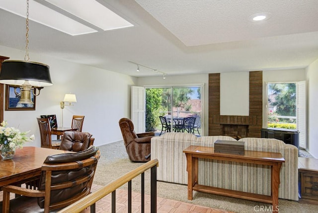 3424 Calle Azul Unit A, Laguna Woods, CA 92637 - living room with a brick fireplace, light carpet, a textured ceiling, track lighting, and recessed lighting