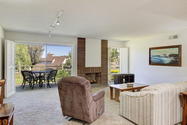 3424 Calle Azul Unit A, Laguna Woods, CA 92637 - living room featuring rail lighting, light carpet, a textured ceiling, healthy amount of natural light, and a brick fireplace