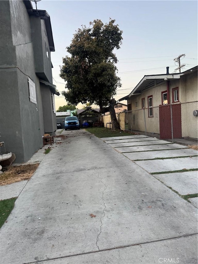 property exterior at dusk with fence, stucco siding, and driveway