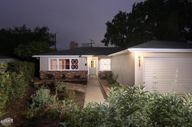 ranch-style home featuring brick siding, a garage, and a chimney