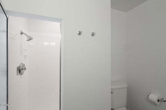 bathroom featuring toilet and a tile shower