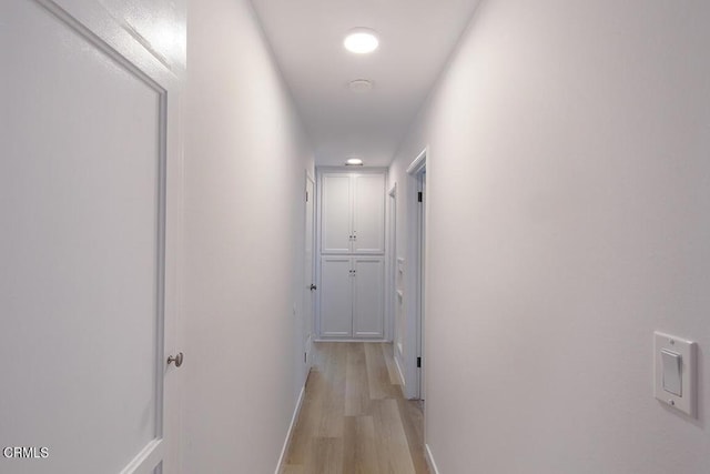 hallway featuring light wood-type flooring and baseboards