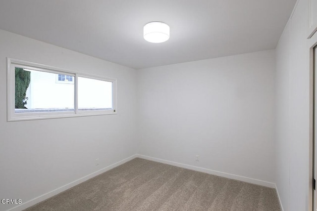 unfurnished room with light colored carpet and baseboards