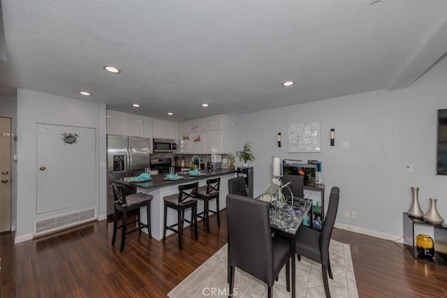 dining area with dark wood finished floors, baseboards, and recessed lighting