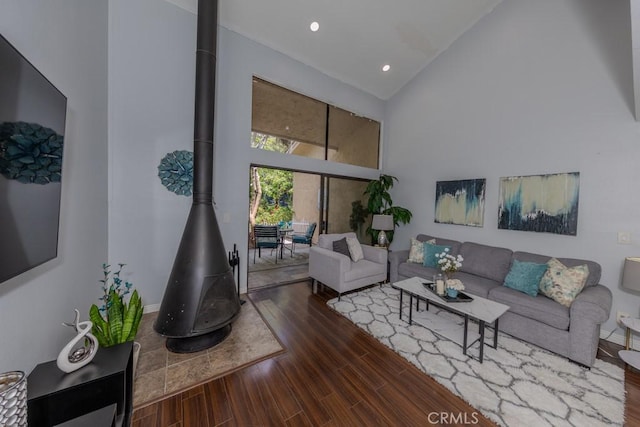 living room with a wood stove, high vaulted ceiling, wood finished floors, recessed lighting, and baseboards