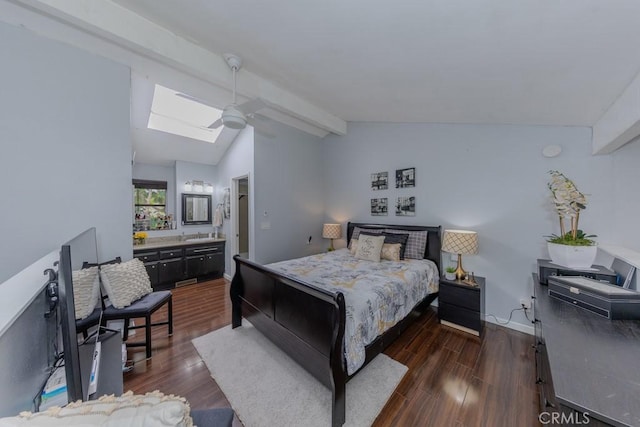 bedroom with a skylight, dark wood finished floors, ensuite bath, a ceiling fan, and baseboards