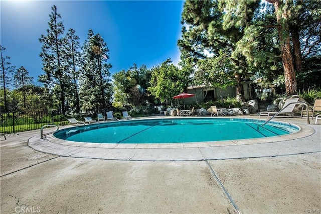 community pool with fence and a patio area