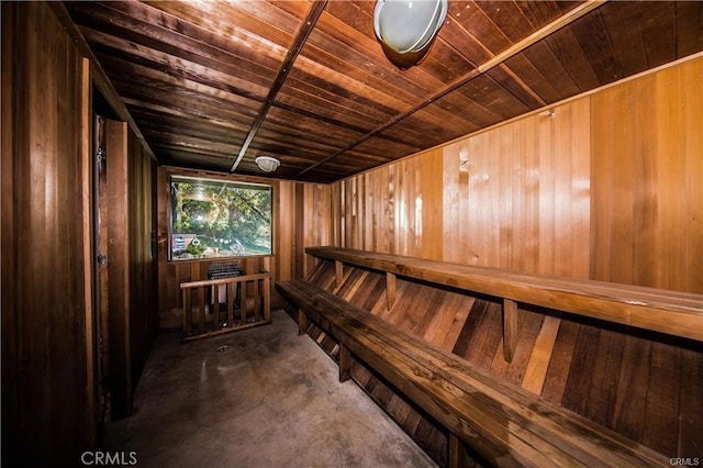 relaxing sauna featuring wooden ceiling, wood walls, and concrete floors