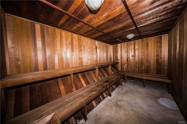 sauna featuring wood ceiling, wood walls, and unfinished concrete flooring
