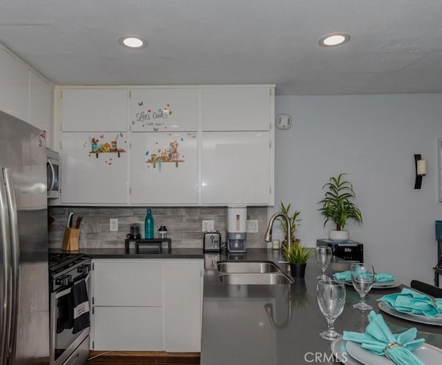 kitchen with stainless steel appliances, a sink, backsplash, white cabinets, and recessed lighting