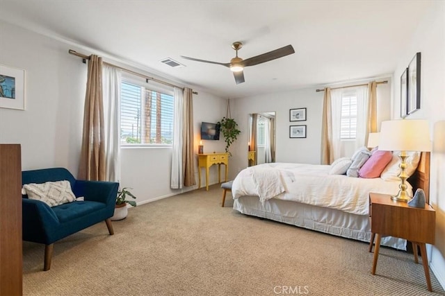 carpeted bedroom featuring multiple windows, baseboards, and a ceiling fan