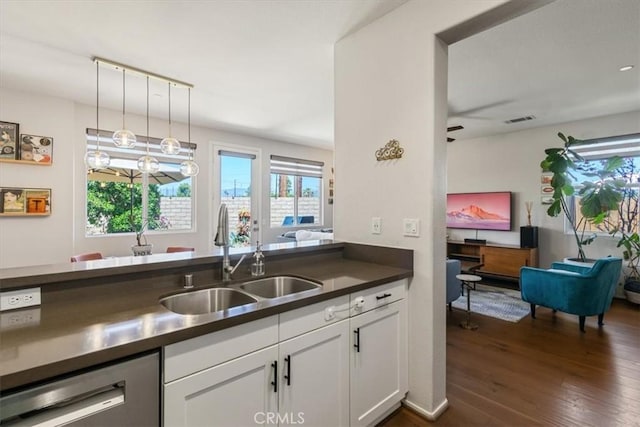kitchen featuring a sink, dishwasher, dark countertops, white cabinets, and dark wood finished floors