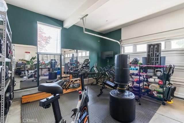 exercise room featuring plenty of natural light, beamed ceiling, and a garage