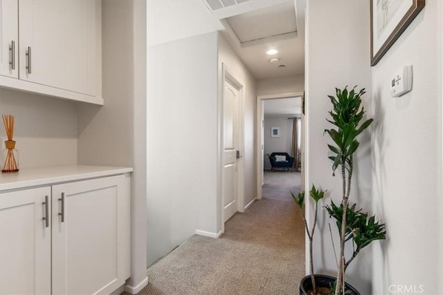 corridor featuring light colored carpet and baseboards