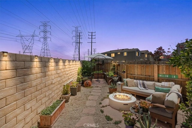 patio terrace at dusk with a garden, a fenced backyard, and an outdoor living space with a fire pit