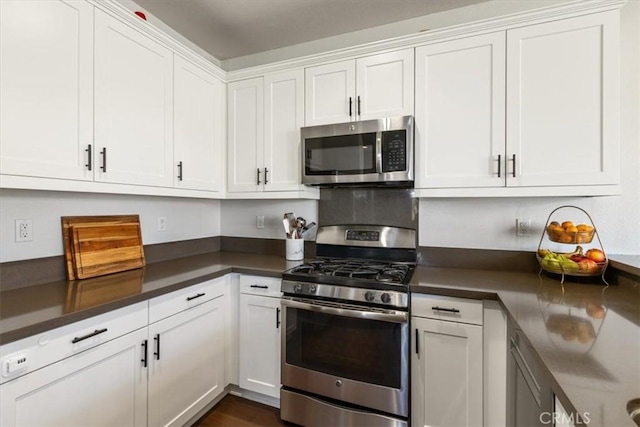 kitchen with appliances with stainless steel finishes, white cabinetry, and dark countertops