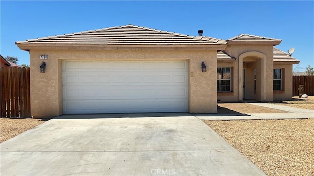 view of front of property featuring driveway, stucco siding, and fence