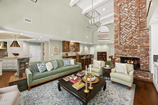 living area featuring high vaulted ceiling, dark wood-type flooring, a fireplace, a chandelier, and beamed ceiling