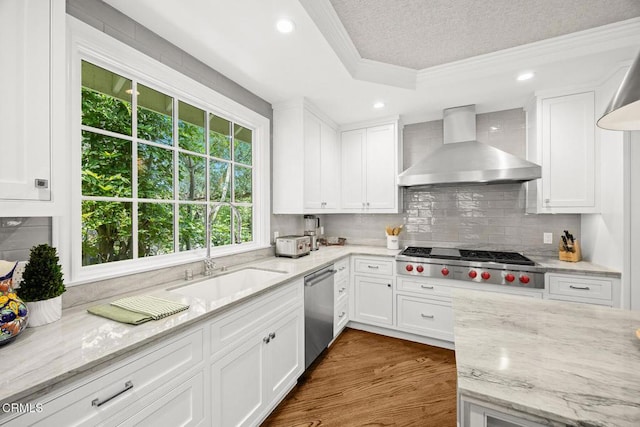kitchen featuring wall chimney exhaust hood, ornamental molding, appliances with stainless steel finishes, white cabinets, and backsplash