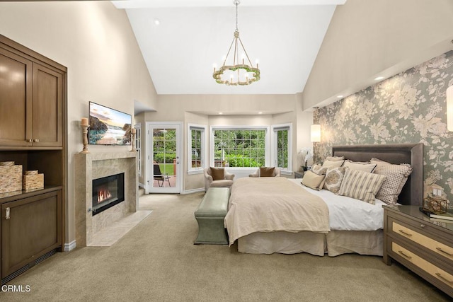 bedroom with light colored carpet, a chandelier, access to outside, a premium fireplace, and high vaulted ceiling