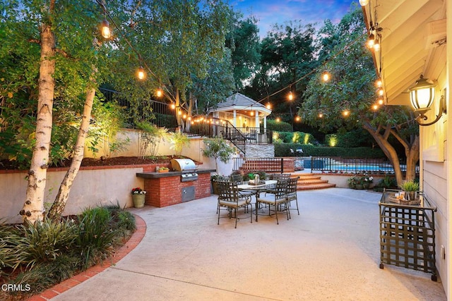 view of patio featuring a gazebo, exterior kitchen, a grill, outdoor dining area, and fence