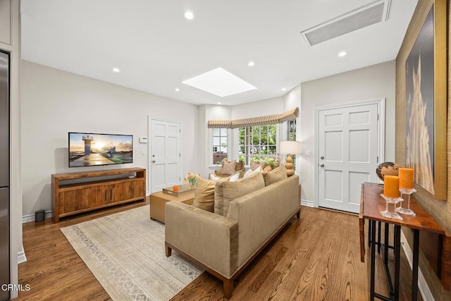 living area featuring wood finished floors, a skylight, recessed lighting, and baseboards