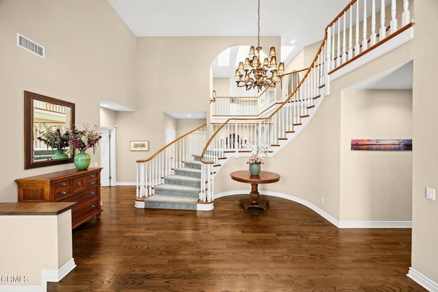 foyer entrance featuring stairs, wood finished floors, a high ceiling, a chandelier, and baseboards