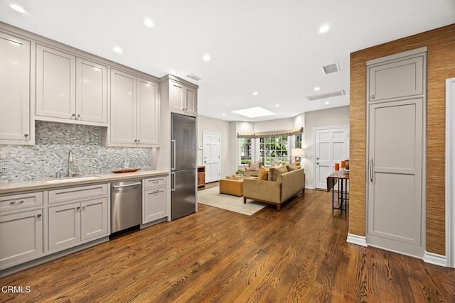 kitchen with stainless steel appliances, a sink, open floor plan, dark wood-style floors, and light countertops