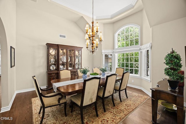 dining space with high vaulted ceiling, a chandelier, arched walkways, plenty of natural light, and dark wood-style floors