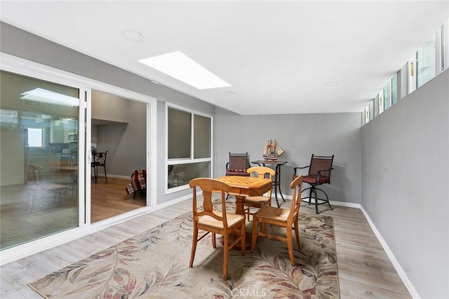 3660 Vista Campana N Unit 11, Oceanside, CA 92057 - dining area featuring light wood-style floors, a skylight, and baseboards