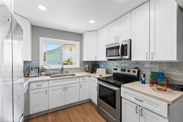 3660 Vista Campana N Unit 11, Oceanside, CA 92057 - kitchen featuring appliances with stainless steel finishes, a sink, light countertops, decorative backsplash, and white cabinetry