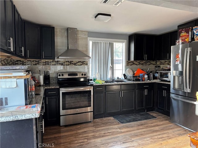 12145 Wanda St, El Monte, CA 91732 - kitchen featuring stainless steel appliances, wall chimney exhaust hood, tasteful backsplash, and dark cabinets