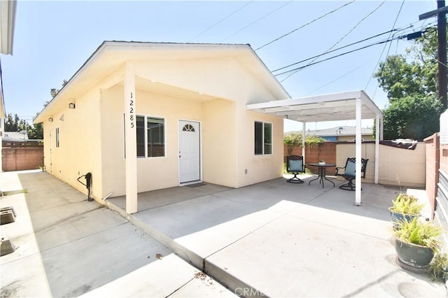 rear view of house with stucco siding, a patio, and a fenced backyard