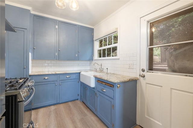 kitchen with blue cabinets, a sink, stainless steel gas range, backsplash, and ornamental molding