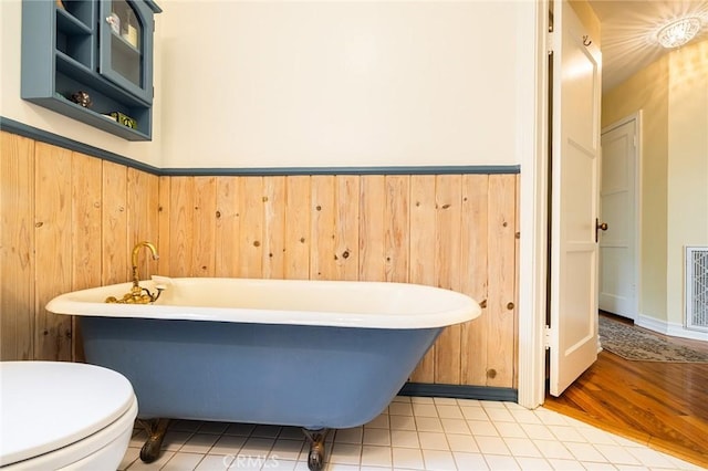 bathroom with toilet and a freestanding tub