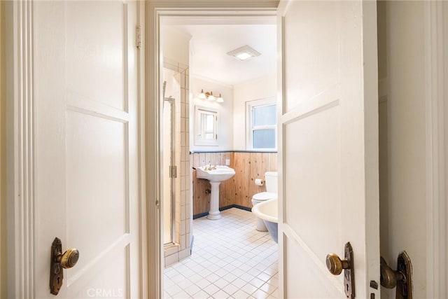 bathroom with toilet, a wainscoted wall, tile patterned flooring, and a bidet