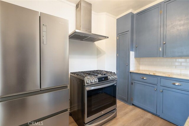 kitchen featuring appliances with stainless steel finishes, wall chimney range hood, blue cabinetry, light wood-style floors, and crown molding