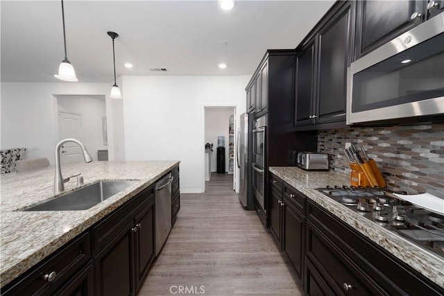 3225 E Denali Dr, Ontario, CA 91762 - kitchen featuring appliances with stainless steel finishes, a sink, backsplash, light stone counters, and light wood finished floors