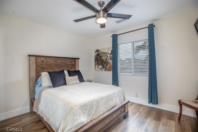 bedroom featuring baseboards, wood finished floors, and a ceiling fan