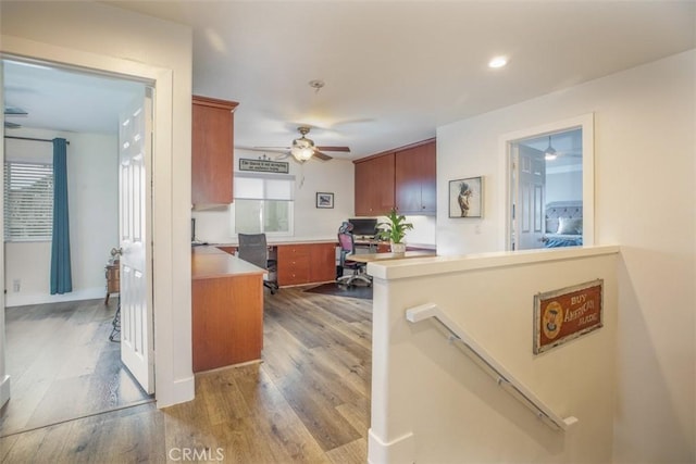 kitchen with a ceiling fan, an office area, wood finished floors, brown cabinetry, and light countertops
